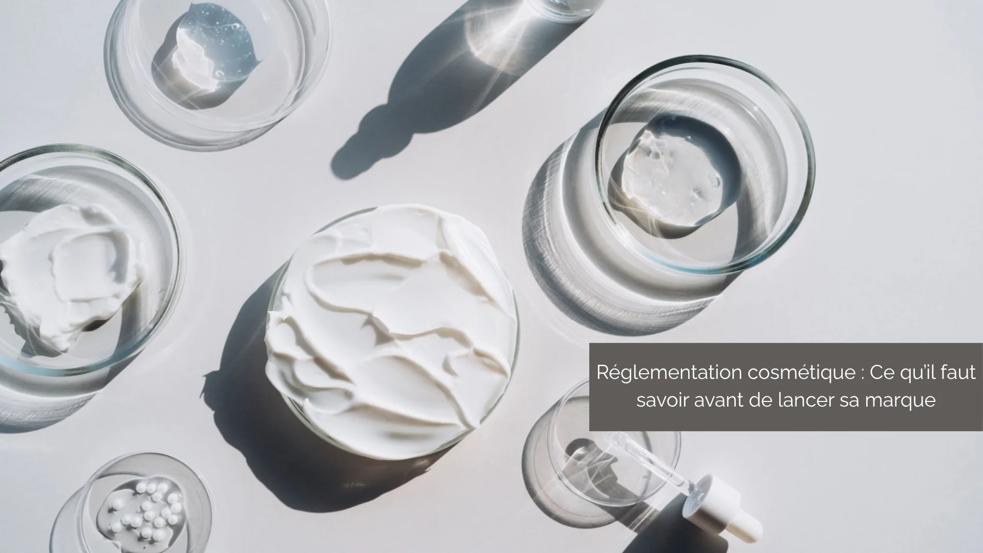 Coupelles de crème, gel et perles sur fond blanc – réglementation cosmétique